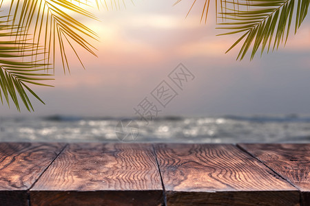 日落的模糊的海上,木桌的顶部椰子树的背景空准备您的产品蒙太奇夏天海滩的海滩背景上的空木桌棕榈叶模糊了背景图片