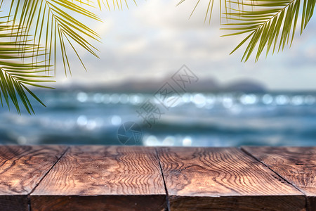 景观景观与旧木桌椰子叶模糊的蓝海白沙滩与清晰的蓝天背景夏季放松聚会海滩模糊背景与棕榈叶背景与老式旧木桌背景图片