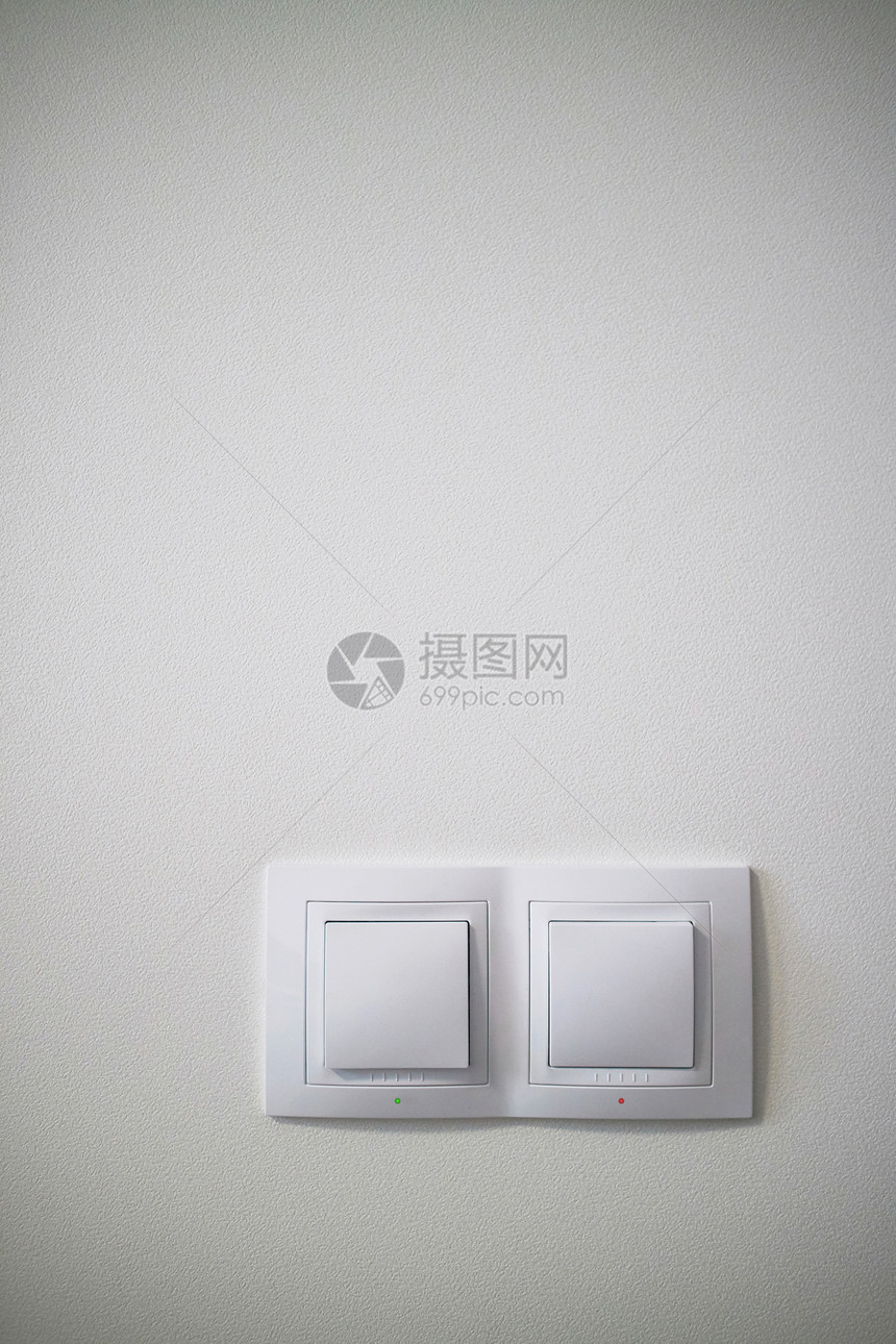 混凝土墙上的双白色照明开关,电源插座插头与切换混凝土墙上的电动两个白色照明开关图片
