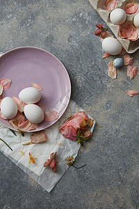 复活节鸡蛋,花纸盘石头背景上粉红色盘子上的白蛋图片