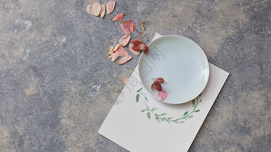 盘子上的干燥花瓣石头背景上的纸上的花框用水彩画框架纸上板图片