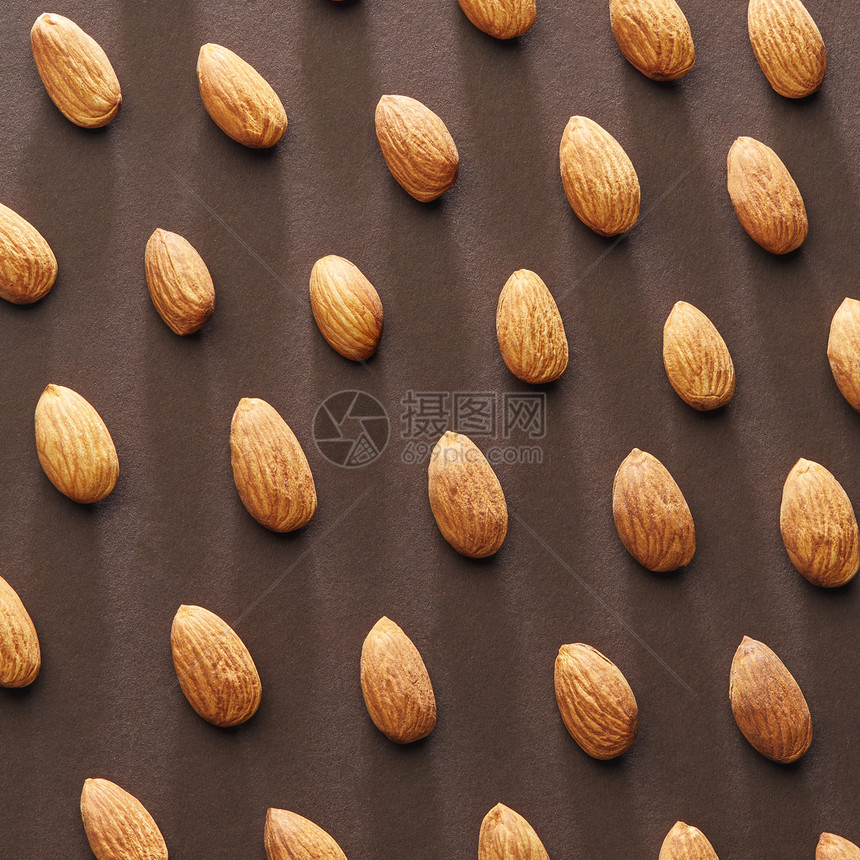 创造的模式皮杏仁阴影反射棕色的纸背景平躺机食品棕色纸背景上的新鲜杏仁坚果的图案图片