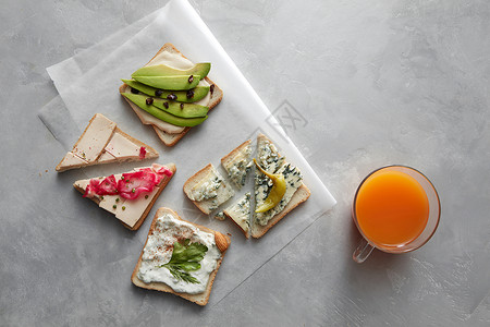同种类的三明治的顶部视图,用于品尝桌子上休息远处的杯橙汁三明治加奶酪鳄梨等同种类的三明治背景