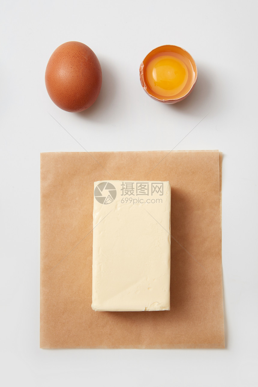 白色背景下的生鸡蛋纸上黄油块的顶部视图黄油鸡蛋图片