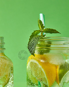 个特写镜头的绿色薄荷个璃瓶与冷的自然手工柠檬水绿色背景冷酒精非酒精夏季饮料的璃瓶中聚焦小串绿色薄荷,背景图片