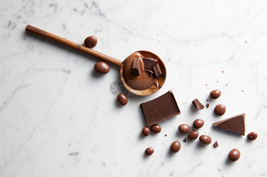 白色大理石背景上焦糖巧克力片巧克力球的木制勺子带巧克力的木勺子图片