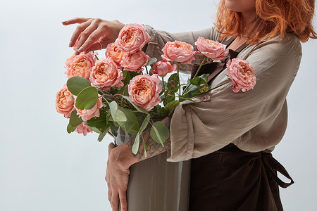 花瓶里的粉红色玫瑰个轻的红发女孩着花瓶花店的红发女孩着个花瓶玫瑰图片