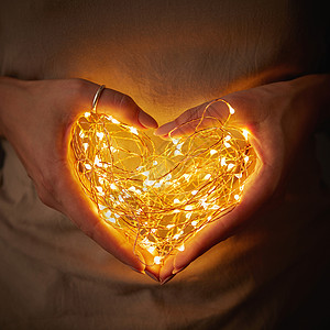 特写灯光的形状颗心,个女人黑暗中牵手情人节的女人着心形的灯图片