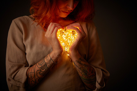 个纹身的可爱女孩黑暗中着花环灯瓦伦丁节女人着心形的灯图片
