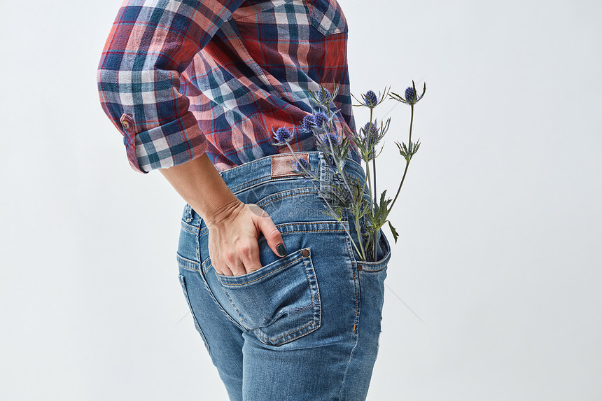 个穿着牛仔裤的女人站她的背上,口袋里放着朵比利时花假期母亲节蓝色花朵的女人图片