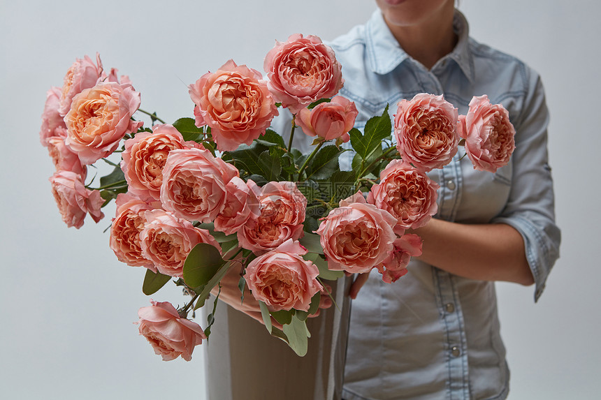 花瓶里明亮的粉红色玫瑰女孩手里着个灰色背景的花盆情人节礼物棕色花瓶里新鲜的粉红色玫瑰图片