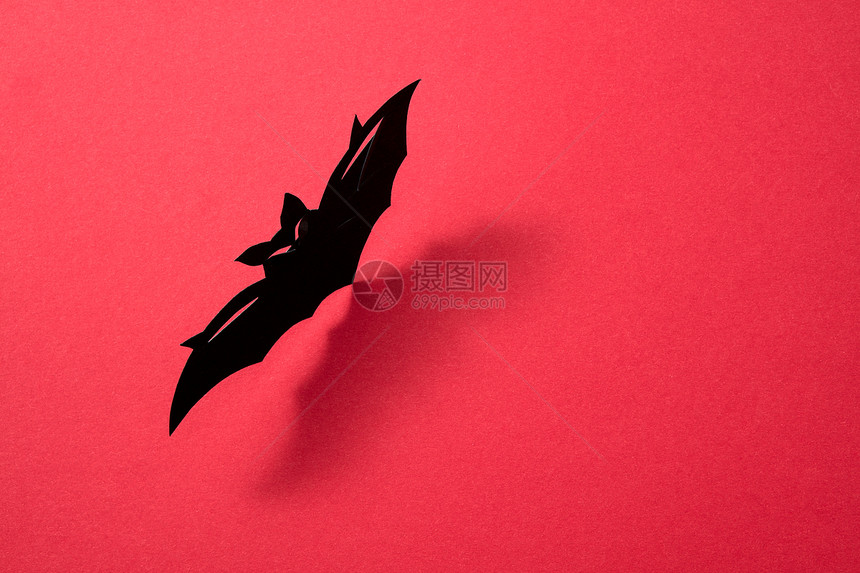 纸飞行手工蝙蝠呈现红色背景上,阴影文字的图案神秘的万节布局平躺手工纸蝙蝠红色背景与阴影的文本图片