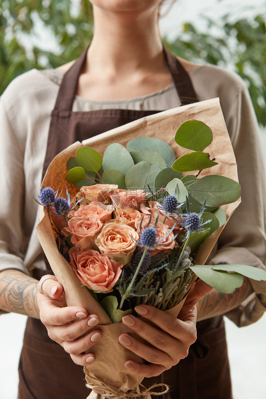 花店的女人带着珊瑚玫瑰绿叶女孩手里着朵花送给母亲的礼物轻女孩着新鲜的天然花,玫瑰比利时绿叶母图片