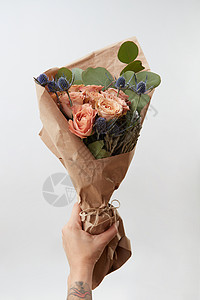 女士的手着漂亮的花,新鲜的芬芳的花中,灰色的背景上,生活着珊瑚色的玫瑰文字的位置母亲节贺卡女手浅色背景背景图片