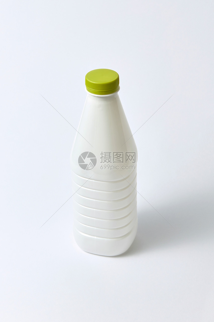 塑料空白白色瓶子,用于牛奶其他液体,绿色帽子浅灰色背景上,塑料浅背景上模拟乳制品瓶图片