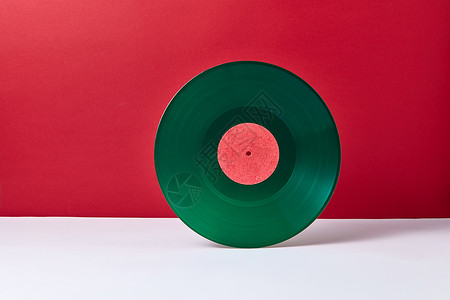 绿色光盘种圆形音乐,绿色乙烯基唱片,背景为双色红色灰色复古音频技术文本的位置老式绿色乙烯基记录磁盘上的双调背景背景