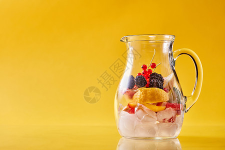 准备自制的清爽冷果冲床璃罐上的黄色背景,寒冷的非酒精夏季饮料的璃罐与柑橘,浆果冰背景背景图片