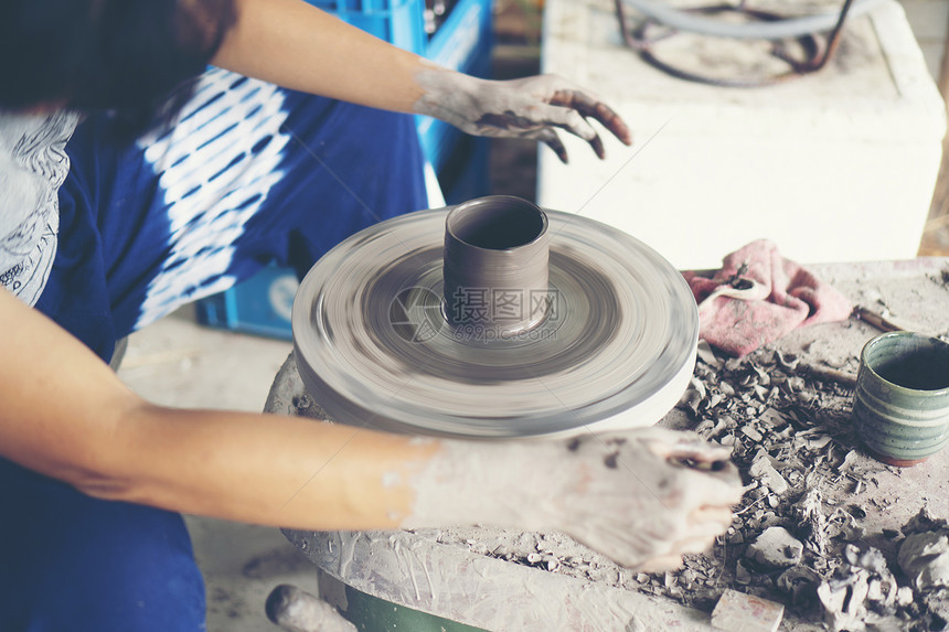 女人的手靠近,熟练的陶瓷工作室用粘土陶工的车轮上工作图片