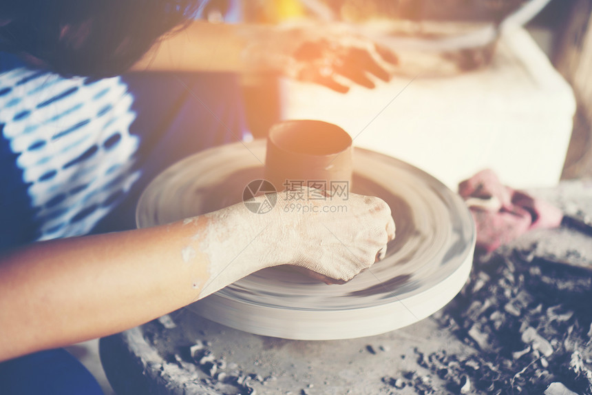 女人的手靠近,熟练的陶瓷工作室用粘土陶工的车轮上工作图片