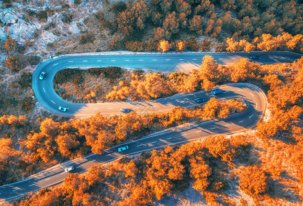 秋林中蜿蜒道路的鸟瞰图,日落山上美丽的沥青道路橘子树的顶部景色公路秋天穿过林地欧洲旅行五颜六色的风景背景图片