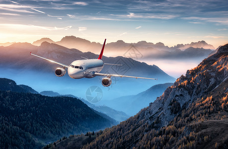 高度决定视野飞机夏天五彩缤纷的日落时,雾中飞过群山风景与客机,小山低云,蓝天白色飞机商务旅行商业飞机空中视野背景