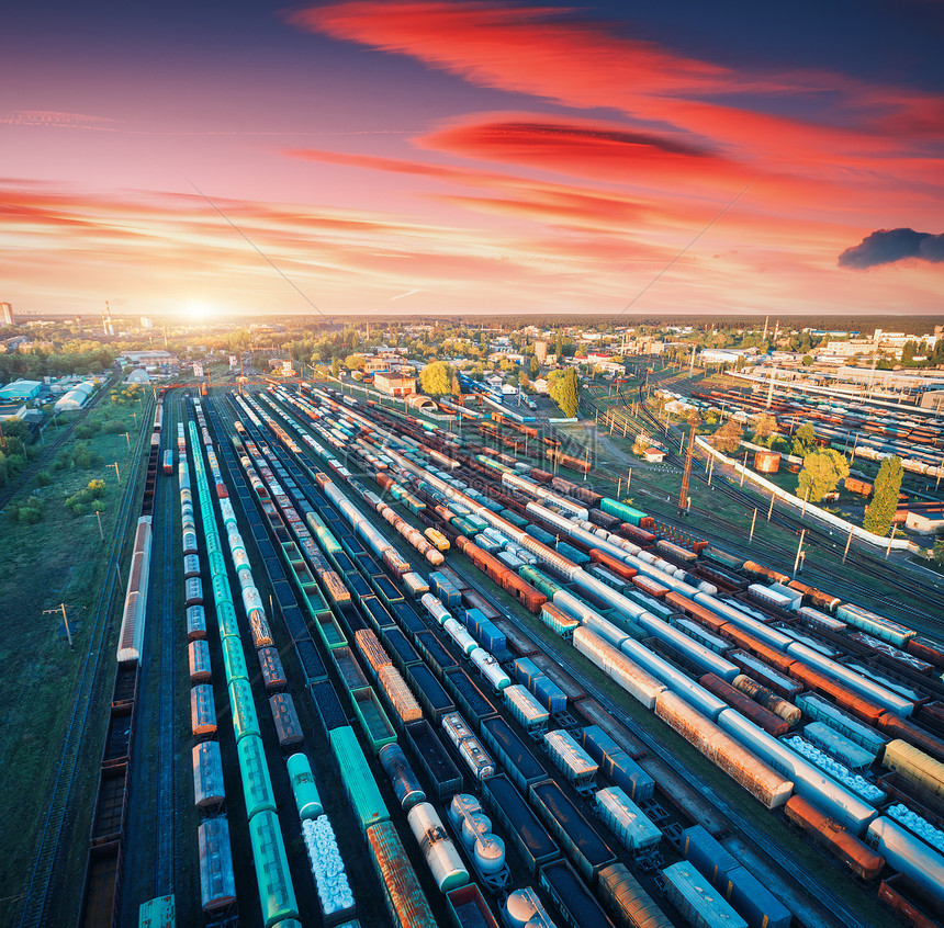 彩色日落火车站货运列车的鸟瞰图铁路上货物的货车重工业工业货运列车,城市建筑紫色天空与红云的风景图片