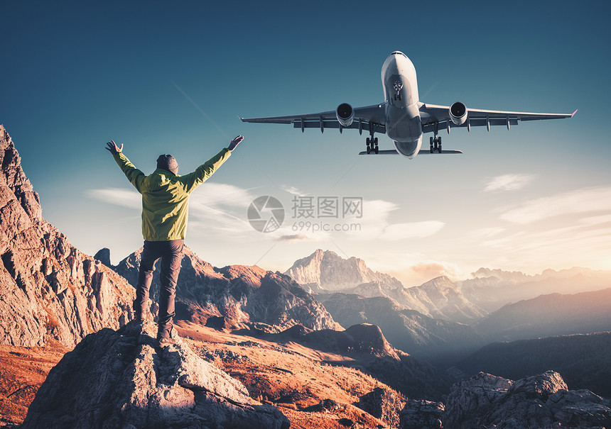 飞机人石头上举手臂日落时抵山快乐的运动人,飞行的客机,岩石蓝天白云石,意大利旅行者着陆飞机图片