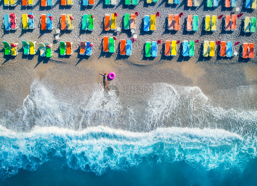 鸟瞰躺海里的女人,带着游泳环,土耳其的Oludeniz夏季海景与女孩,蔚蓝的水,波浪沙滩与五颜六色的躺椅阳光明媚的日图片