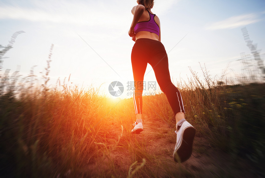 轻的女人夏天的田野里日落时跑乡村的路上生活方式体育背景图片