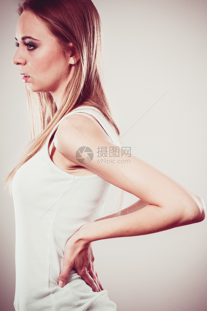 长时间的工作时间健康背痛的轻女背部疼痛的女人灰色图片