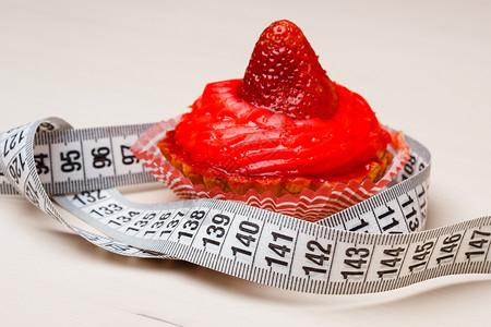 食欲贪食的育肥问题桌上测量带的蛋糕纸杯蛋糕背景图片