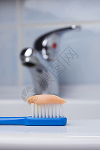 牙科保健健康特写蓝色刷子牙刷与粘贴浴室的水槽,水龙头背景图片