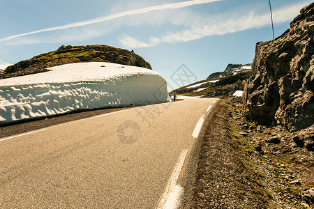 游客妇女拍照高雪墙山路极光挪威,夏季时间游客挪威路的高雪墙上拍照图片