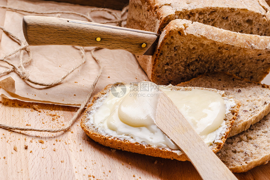 鲜活的全麦包与黄油蜂蜜乡村木桌背景图片
