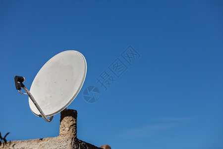 电视屋白色卫星碟,背景蓝天家庭屋顶上的电视天线无线技术数字设备蓝天上的卫星天线背景