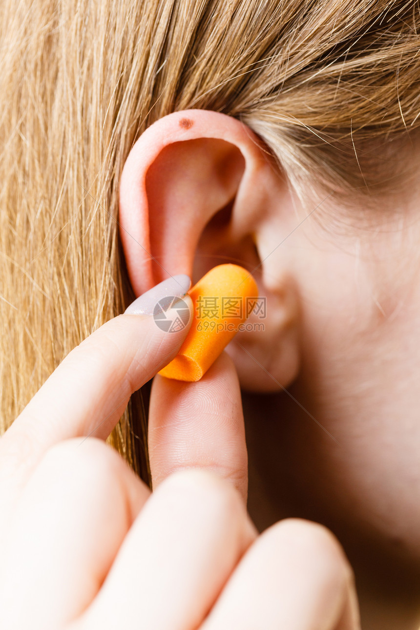 女人把耳塞塞进耳朵里,响亮的地方消除噪音女人把耳塞图片