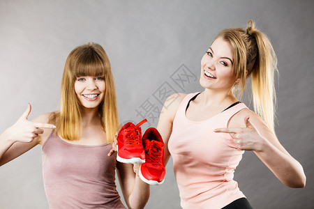 两个快乐的运动微笑的女人展示运动服装运动鞋红鞋,舒适的鞋类完美的锻炼训练两个女人展示运动服装运动鞋背景图片