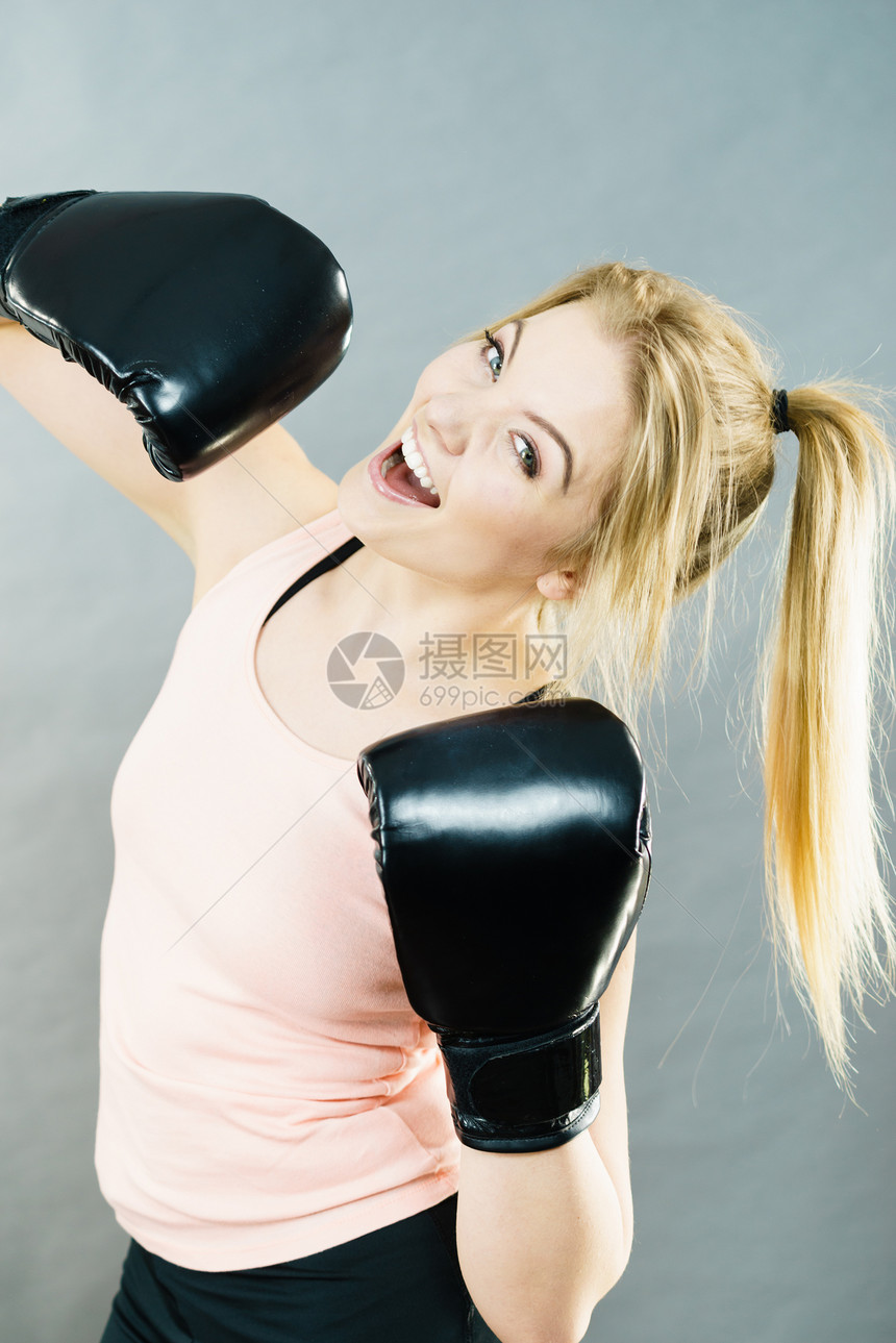 运动的女人戴着黑色的拳击手套,打架工作室灰色背景上拍摄戴拳击手套的快乐微笑的女人图片
