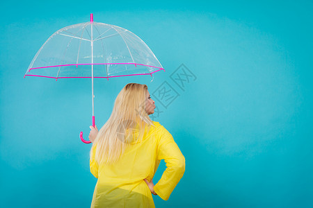 雨天秋日配饰理念金发女人穿着雨衣,着透明的伞,背景金发女人着透明的伞图片