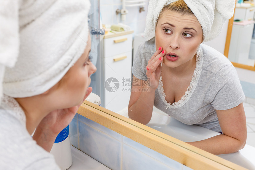 忧虑震惊的女人看着镜子里的倒影,思考着她的情结,她严肃的部表情,分析着脸的肤色女人看着镜子里的倒影图片