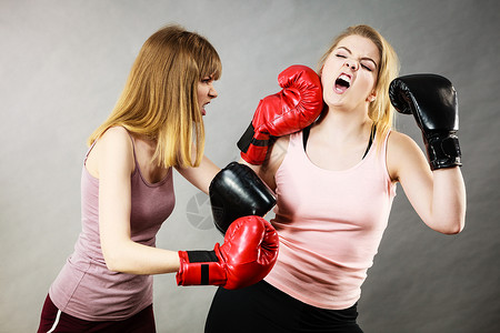 爸气方刚两个好斗的女人戴着拳击手套,争论着打架,互相生方的气女中提琴两个好斗的女人打拳击背景