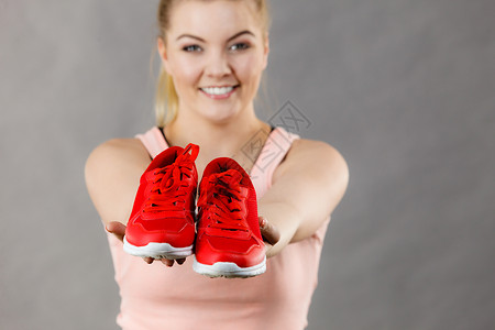 快乐的运动微笑的女人展示运动服装运动鞋红鞋,舒适的鞋类完美的锻炼训练快乐的女人展示运动服装运动鞋背景图片