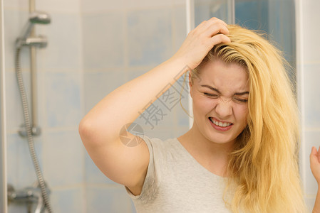 油腻头发金发女人问题,油腻的油头发看着自己浴室女露出头皮,挠自己,头皮屑问题女金发问题背景
