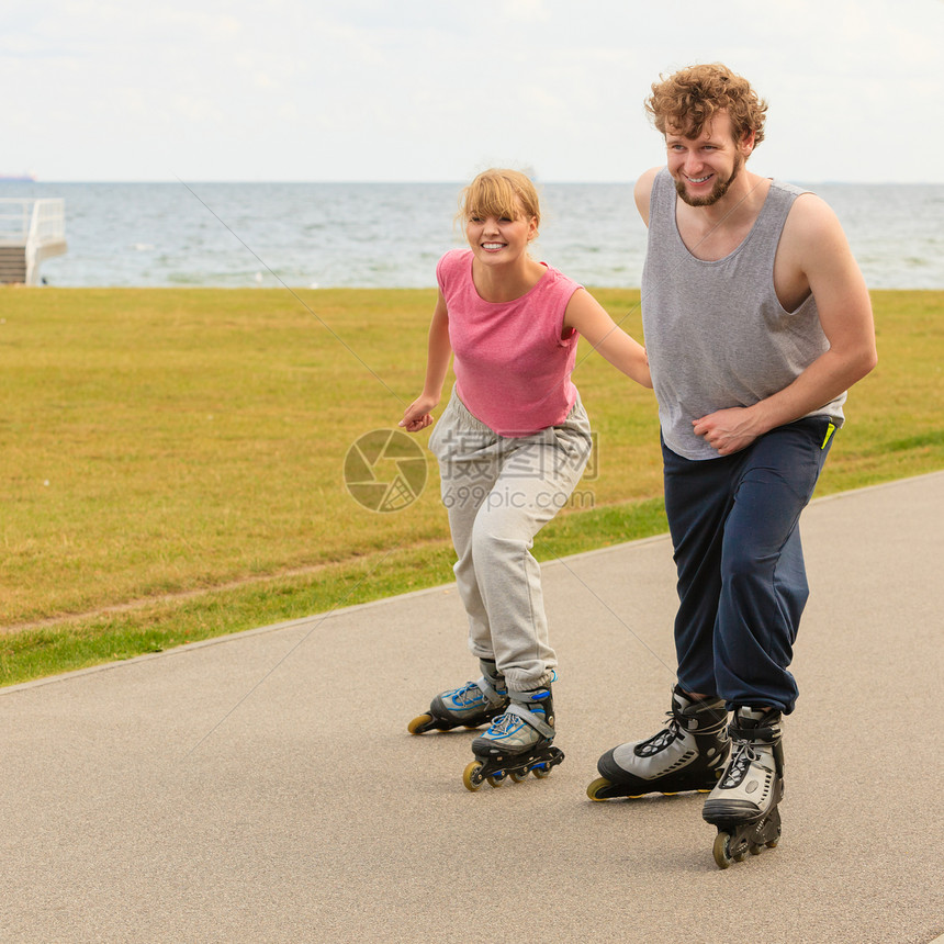 积极的生活方式自由观念穿着溜冰鞋的轻夫妇海边户外骑马,女人男人享受时光溜冰夫妇户外滑冰图片