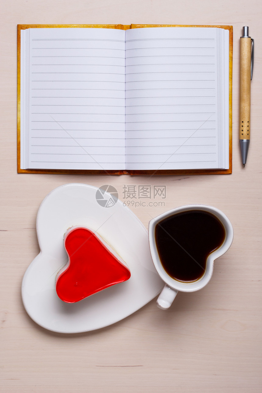 咖啡杯果冻蛋糕的形式,心纸空笔笔记本与笔桌子上,顶部视图的文本图片