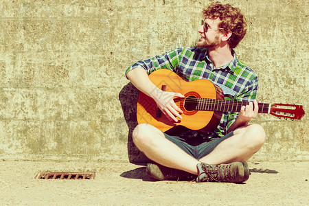 音乐人的轻的留着胡子的时髦男人,街上带着吉他图片