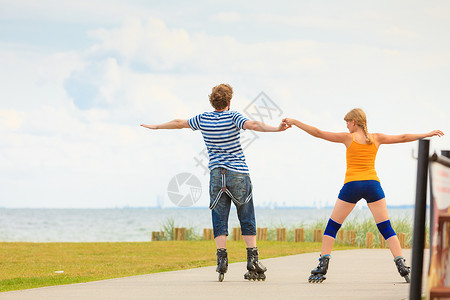 节日,积极的人友谊的轻的穿着溜冰鞋的夫妇骑海边的户外,女人男人长廊上滑行背景图片