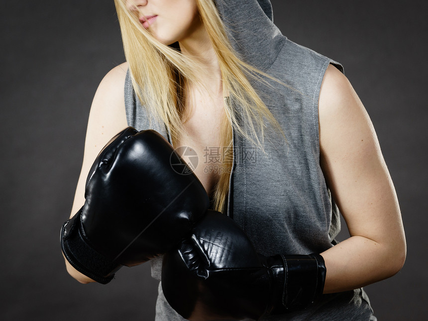 运动的女人戴着黑色的拳击手套,打架录音室黑暗背景下拍摄戴拳击手套的女人图片