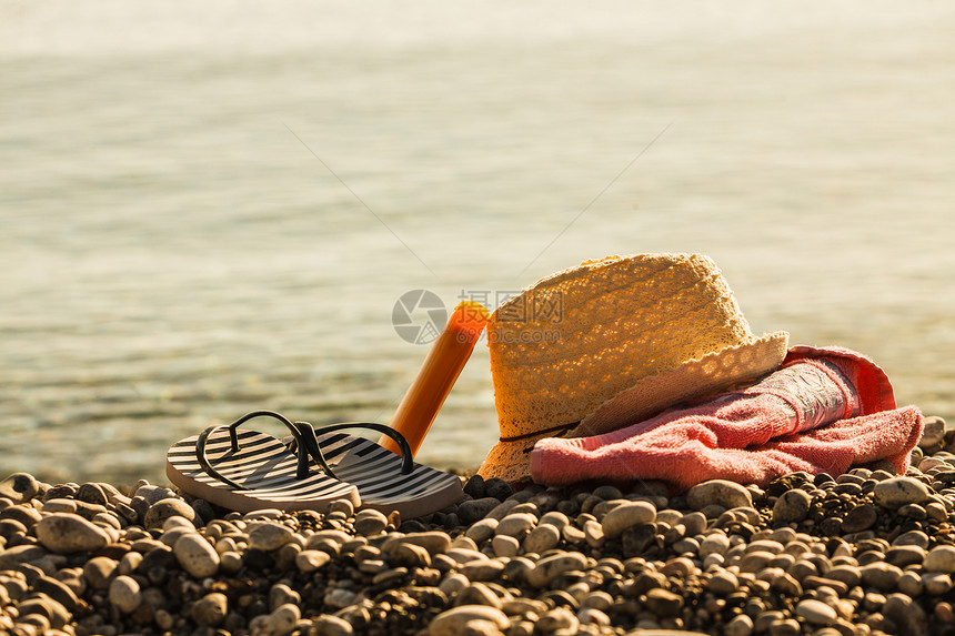 沙滩配件毛巾上进行日光浴阳光明媚的帽子拖鞋,石头石头沙子太阳帽拖鞋石滩上图片