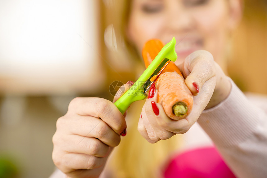 女人用食物剥皮机剥蔬菜烹饪女上菜前先准备胡萝卜图片